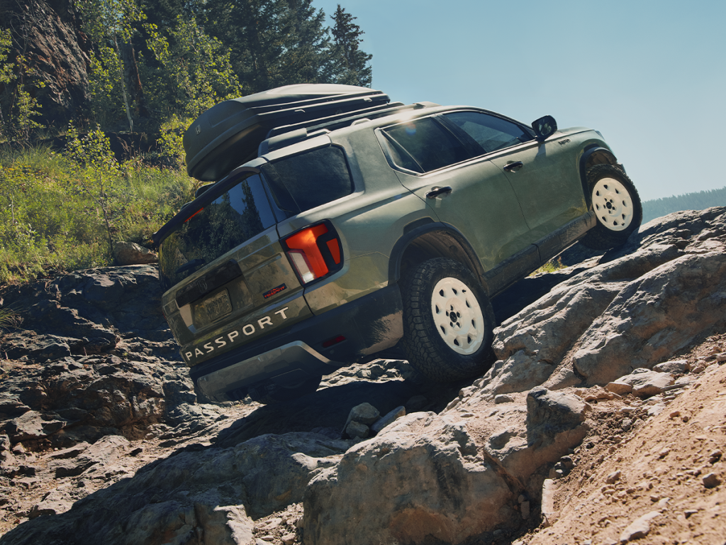 A 2026 Honda Passport driving off-road up rocky terrain