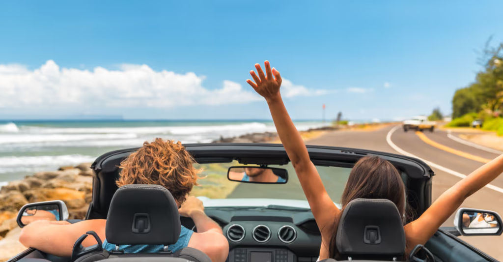 A driver and passenger enjoy a convertible driving along the beach as they road trip for the summer. Get your roadtrip service at Royal Honda near New Orleans today.