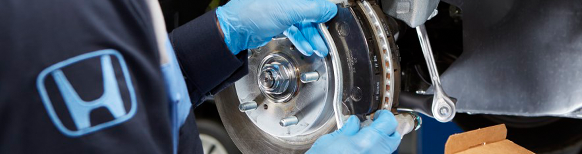 A close-up of a Honda service technician performance vehicle maintenance on a car's tire
